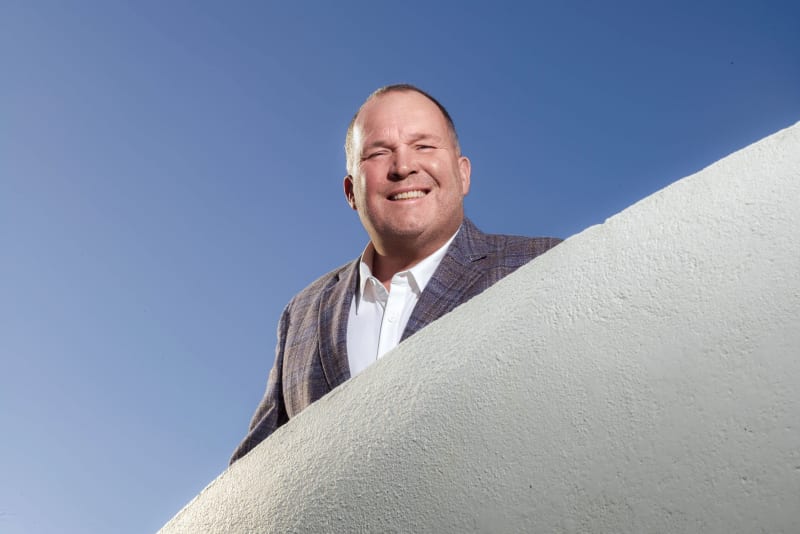 Paul Connell, CEO of Pure Telecom, smiling outdoors against a clear blue sky.