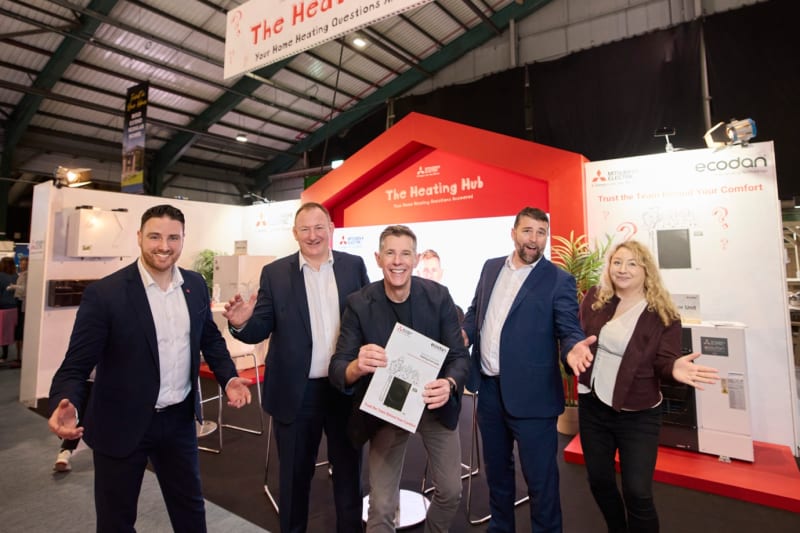 Five people posing at Mitsubishi Electric's Heating Hub exhibition stand featuring Ecodan heat pump products.