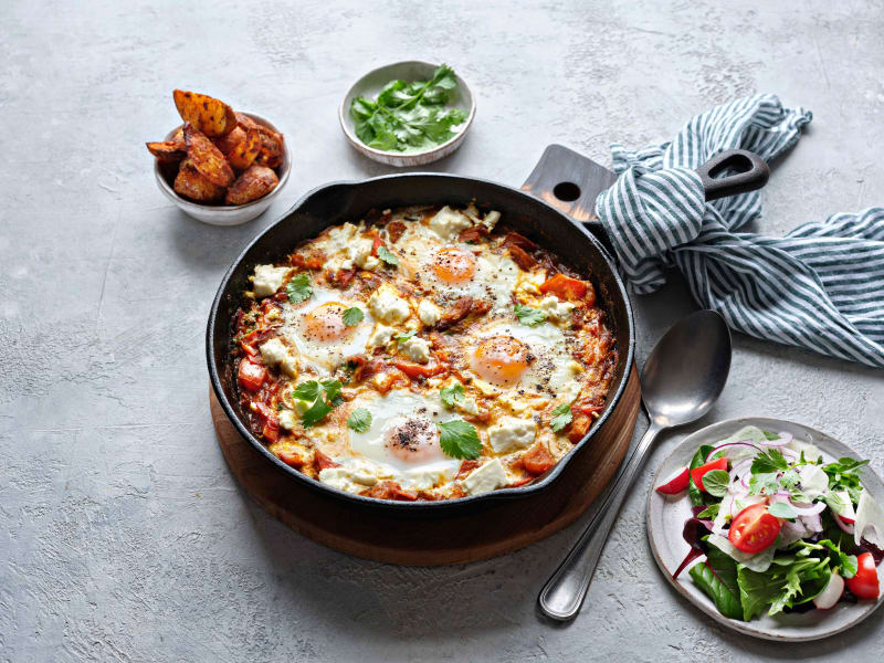 Baked eggs with feta and harissa in a dish.