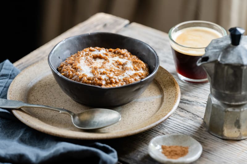 A bowl of Bulletproof Porridge with espresso, cinnamon and honey alongside a moka pot.