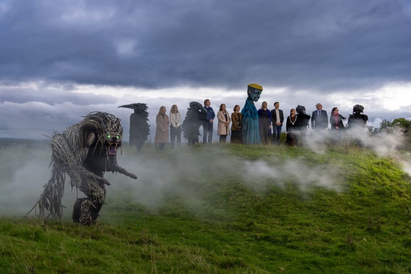 Púca festival 2026 launch event at Meath with giant beast puppet, crow and spirit puppets amid mist on a green hillside.